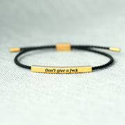Bracelet with gold bar and black cord on a light gray background